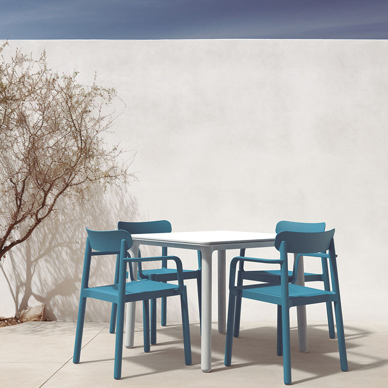 Conjunto de mesa blanca Noa y sillas azules Elba de Resol en terraza exterior de diseño moderno.