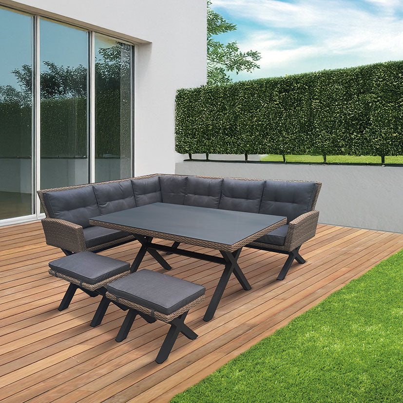 Conjunto de jardín rinconero Pascua en ratán sintético gris con mesa alta y cojines acolchados en terraza de madera.