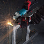 Uso profesional de amoladora Makita GA4530R cortando estructura metálica con generación de chispas.