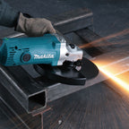 Operario utilizando amoladora Makita GA9050R para cortar estructura metálica con gran desprendimiento de chispas.