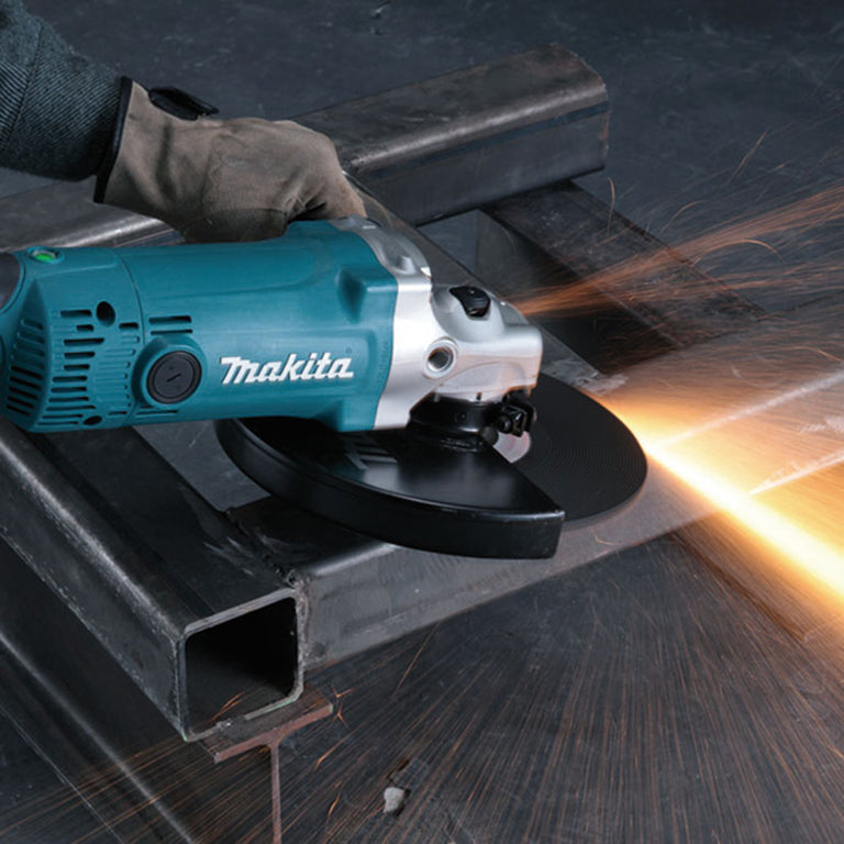 Operario utilizando amoladora Makita GA9050R para cortar estructura metálica con gran desprendimiento de chispas.