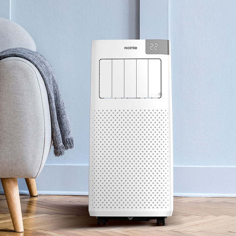 Climatizador portátil Rointe Fiore 2250 ubicado en un salón moderno junto a un sofá.