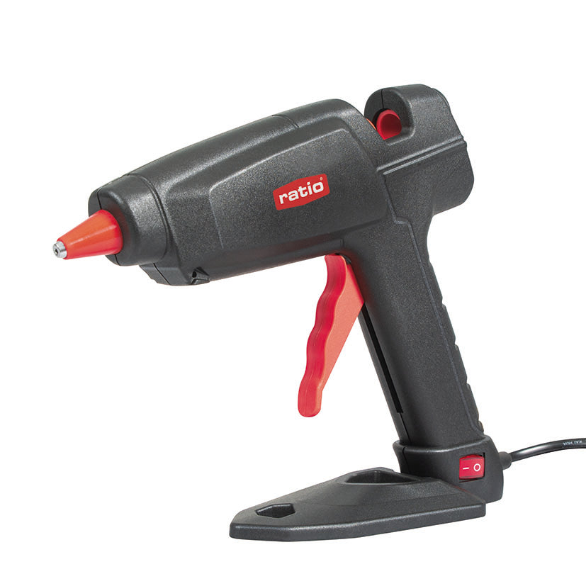 Pistola termoencoladora RATIO R-P100 de 100W con base de apoyo y boquilla de silicona roja.