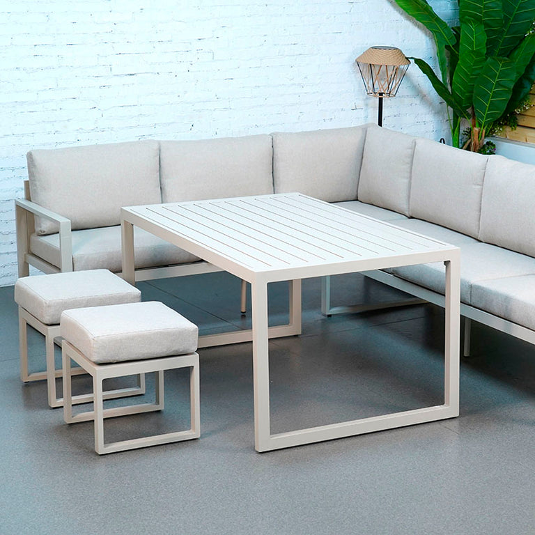Conjunto de jardín esquinero Liam en aluminio blanco con sofás, mesa y puffs en tela gris claro.