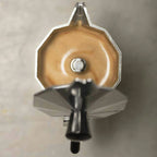 Primer plano superior de cafetera moka Oroley con café espresso recién preparado y espuma