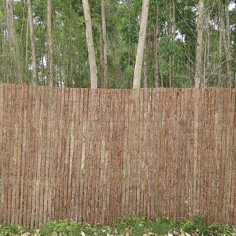 Valla de ocultación fabricada con rollos de corteza de pino natural LISTA instalada en un entorno boscoso.