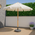Parasol de madera de 3 metros color crudo con mástil de abeto barnizado en terraza con seto verde.
