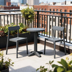 Set de balcón IVY de RESOL compuesto por mesa y sillas apilables en una terraza urbana con plantas.