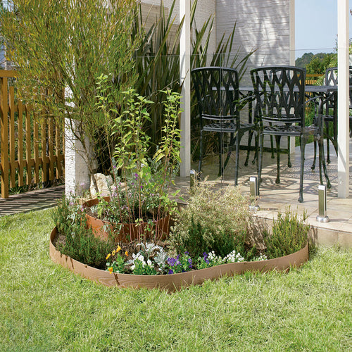 Aplicación de bordura flexible de composite delimitando un parterre con flores y plantas en un jardín.