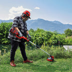 Hombre utilizando la desbrozadora Einhell 36V para cortar hierba alta en un entorno natural cerca de un río.