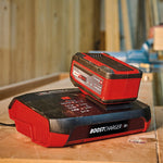 Batería Einhell Power X-Change de 18V conectada al cargador rápido de 8A en un banco de trabajo.