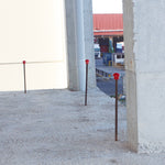 Instalación de setas de seguridad rojas TAYG sobre varillas de acero en una obra de construcción para prevención de riesgos.