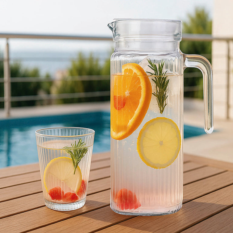 Primer plano de jarra y vaso Chrysler con agua y frutas cítricas en ambiente de terraza con piscina.
