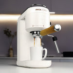 Cafetera JOCCA Nature preparando café espresso doble en taza blanca con vaporizador lateral de acero inoxidable.