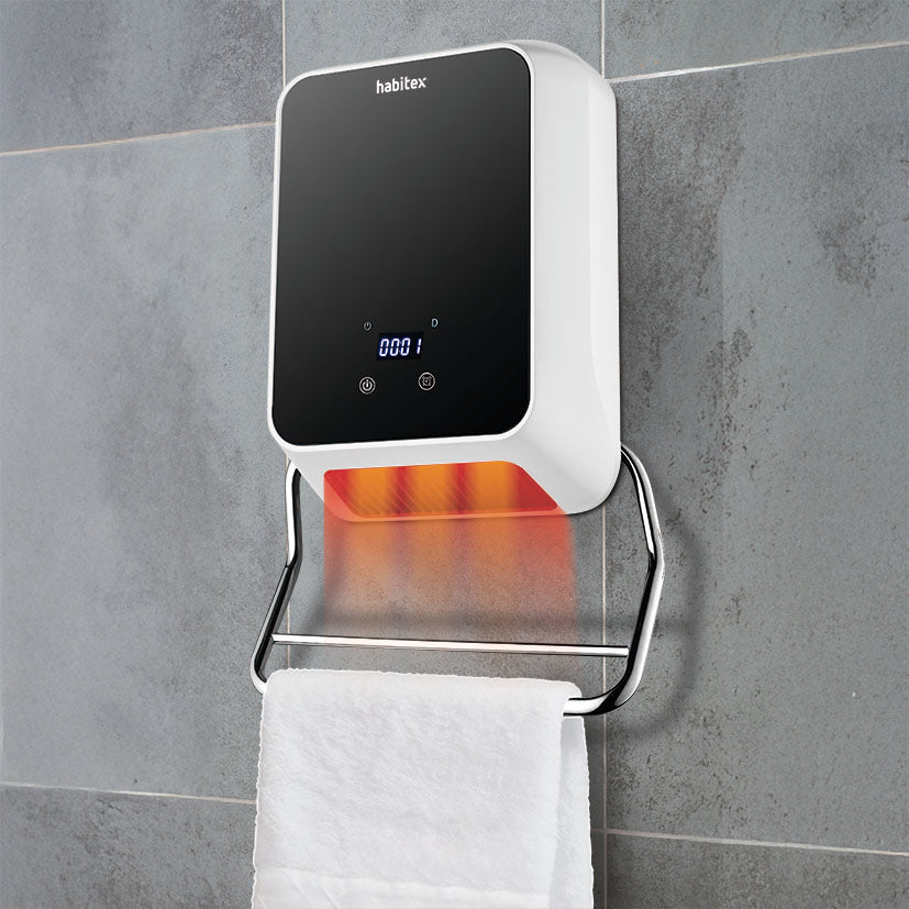 Calefactor toallero HABITEX instalado en pared de baño emitiendo calor sobre toalla