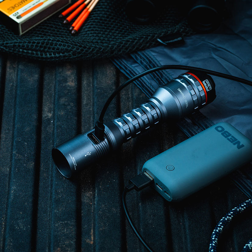 Linterna NEBO Davinci 800 cargándose mediante cable USB-C en un entorno de acampada.