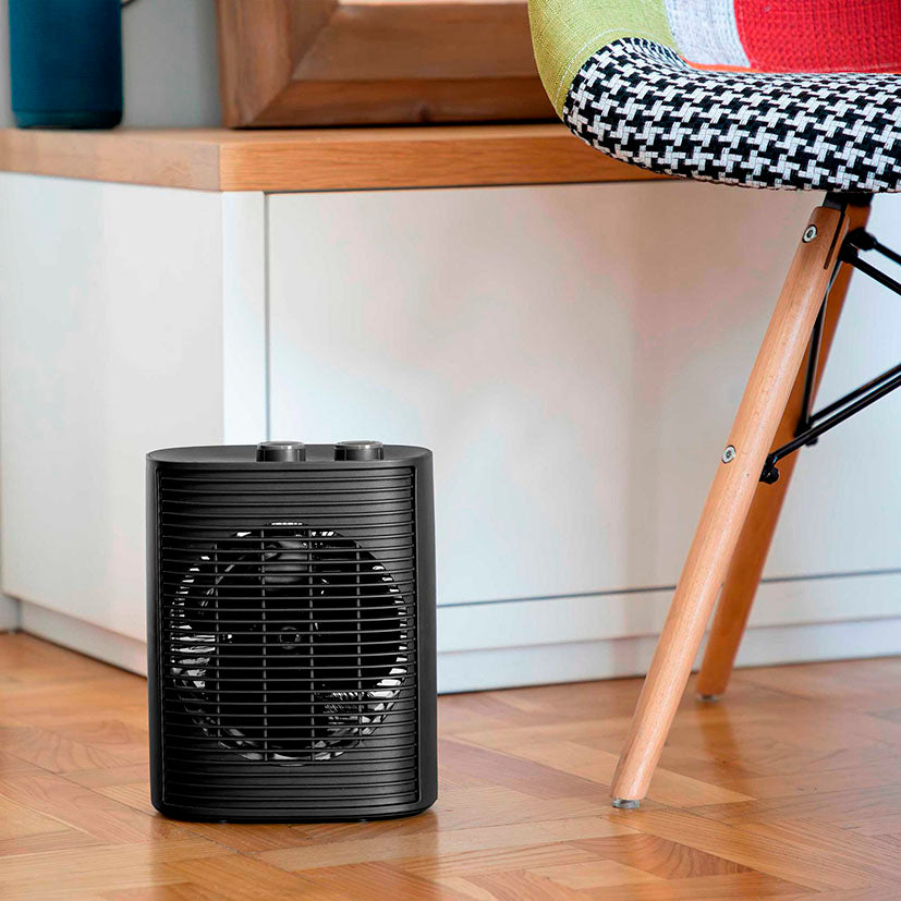 Calefactor JATA JCTV1193 en ambiente doméstico junto a una silla sobre suelo de madera