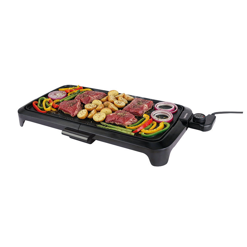 Plancha eléctrica Habitex CC400 cocinando carne, patatas y verduras en su superficie antiadherente
