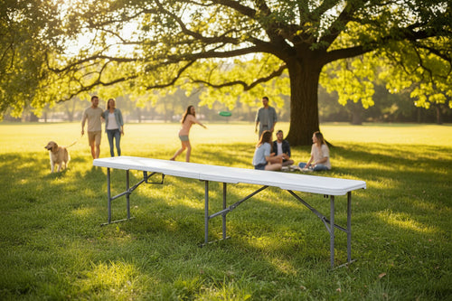 Banco largo de polietileno blanco de 182 cm totalmente extendido con patas de acero gris y refuerzos metálicos visibles, ideal para eventos de exterior.